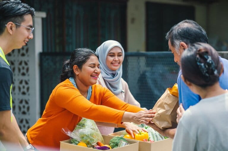 Volunteers from multi-ethnic group provide free food to needy families and local community at outdoor food bank charity campaign