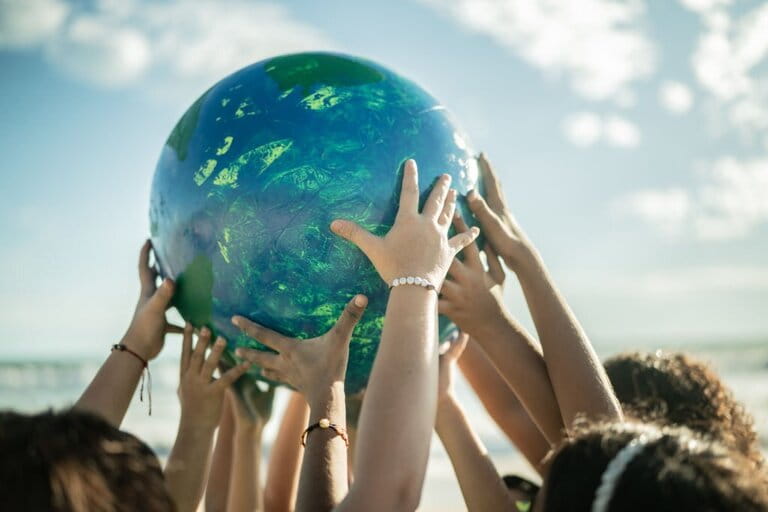Close-up of children hugging a planet on the beach symbolizing environmental protection