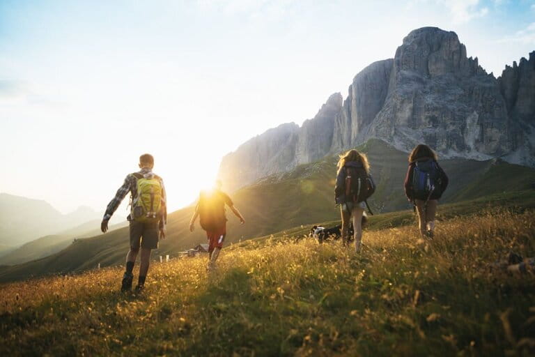 Adventures on the Dolomites: teenagers hiking with dogs in the shimmering dawn